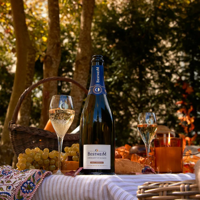 Crémant d’Alsace Bestheim Brut Premium servi à l’apéritif en extérieur, avec des coupes et du raisin