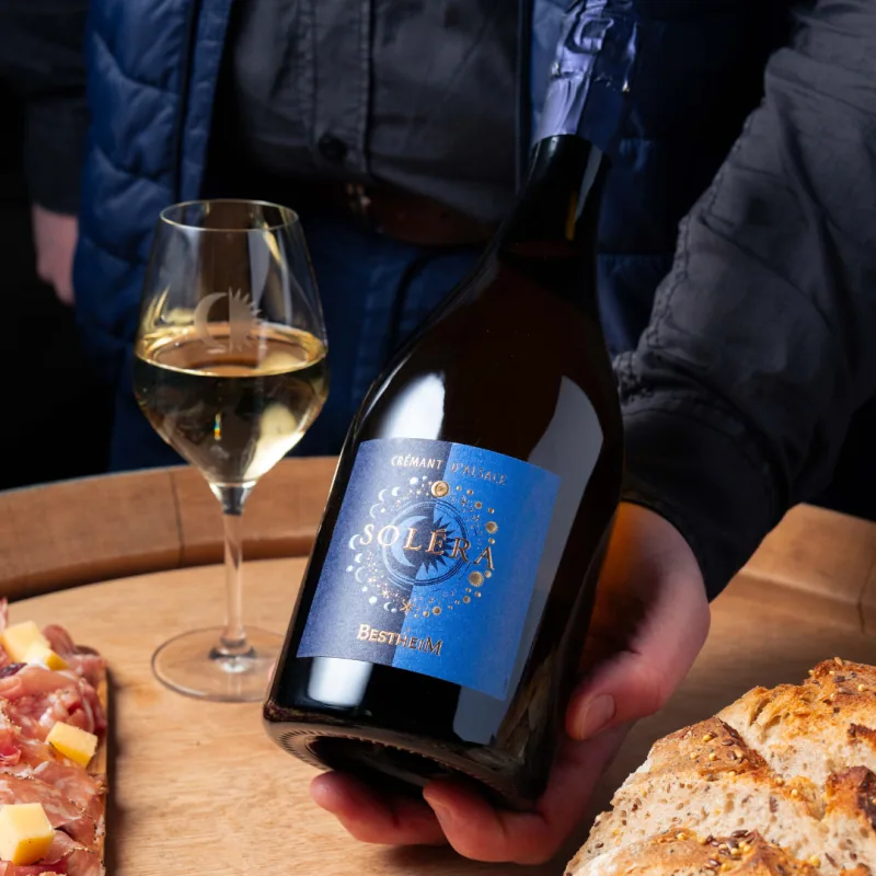 Bouteille de Crémant Soléra Bestheim servie avec un verre de crémant, du pain et de la charcuterie