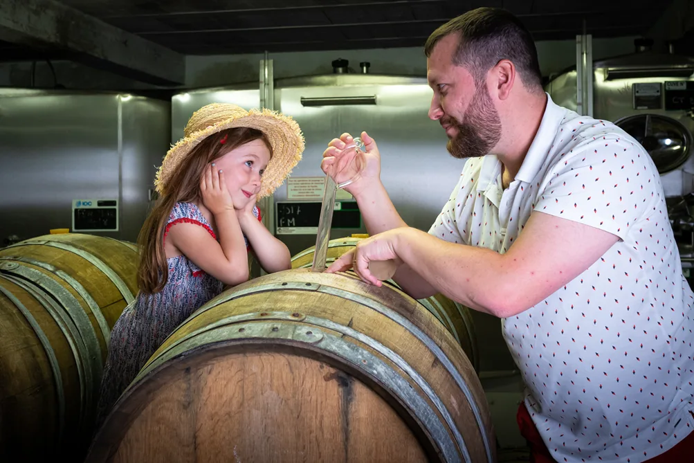 Guillaume Lemaire prélevant du vin à la pipette dans un fût de chêne, avec Louna